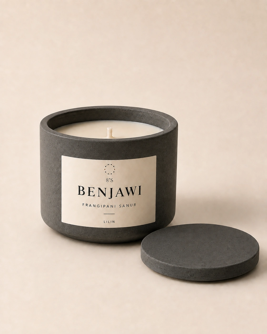 Benjawi Frangipani Sanur candle in a round charcoal concrete vessel, with ivory wax and a matching concrete lid beside it