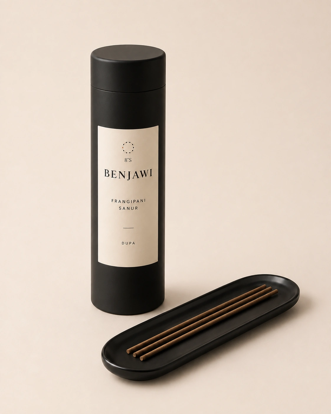 Frangipani Sanur dupa in a cylindrical black canister beside incense sticks and a tray.